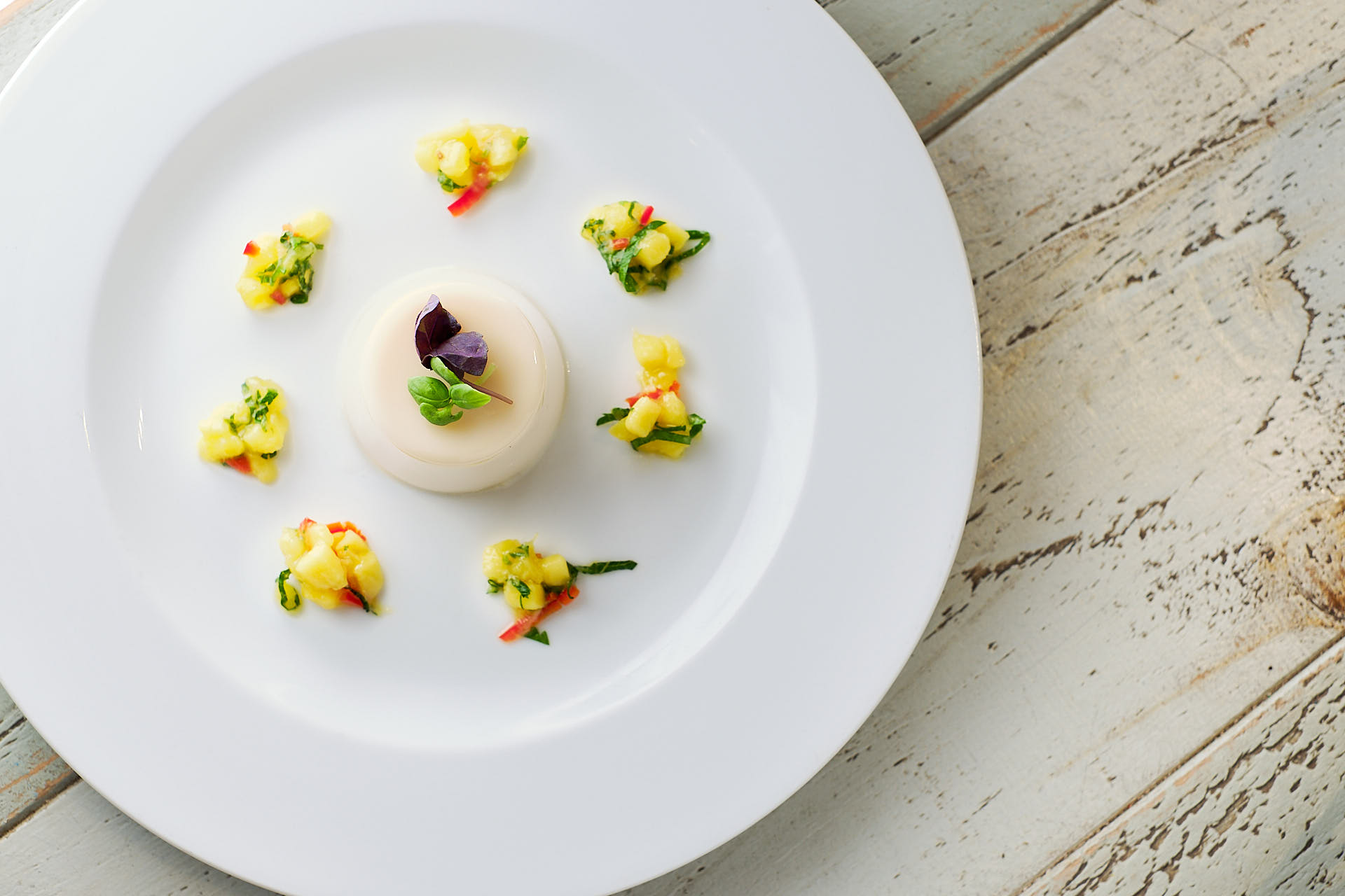 A panacotta dessert with mango and edible flowers.